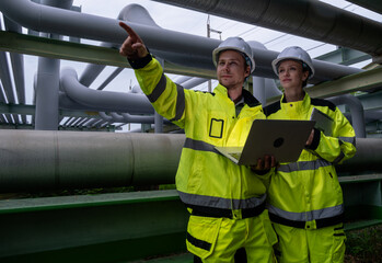 Engineers assess pipeline system in industrial facility during overcast day