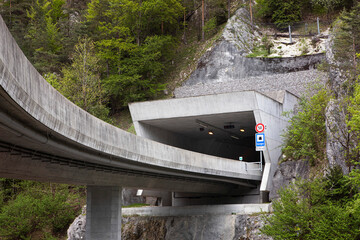 Entrance to a tunnel on a highway, pass trough mountain. Entry from flyover to road tunnel, highway in mountains, drive through mountain range and extreme terrain in Switzerland.