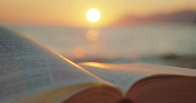 Open book on a beach illuminated by sunset light in summer warm evening