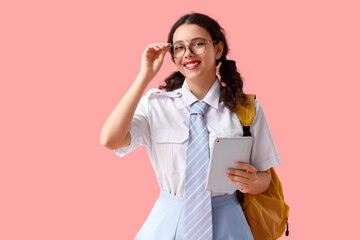 Female Indian student in eyeglasses with tablet computer on pink background