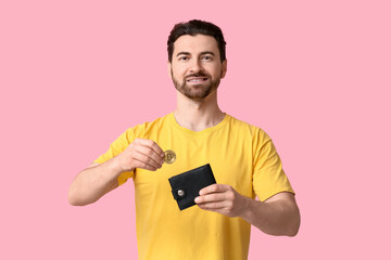 Handsome man putting bitcoin into wallet on pink background