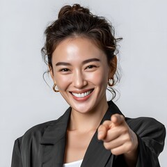 Happy woman in black blazer points directly at viewer