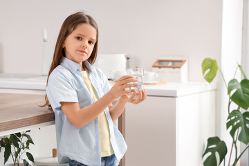 Cute girl with glass of water in kitchen