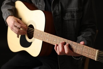 Fototapeta premium Man playing guitar on black background, closeup