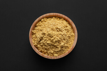 Dry ginger powder in bowl on dark table, top view