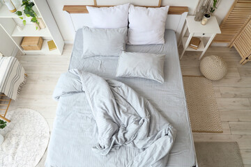 Cozy bed with soft pillows and crumpled grey blanket in bedroom, top view