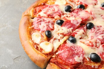 Tasty pizza with salami, cheese and olives on grey table, closeup