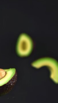 Vertical video sliced avocado, floating in the air, food professional video on black background