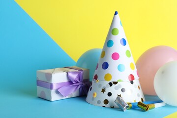 Beautiful party hats and other festive decor on color background