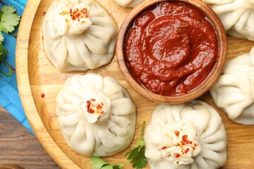 Delicious khinkali served with sauce on wooden table, top view
