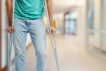 Man with axillary crutches in hospital, closeup. Space for text