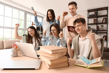 Group of happy students studying with laptop at table in library