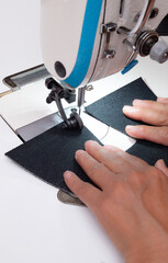 A woman's hands sewing fabric with an industrial sewing machine in a shoemaking workshop. Close-up of the manual labor and textile manufacturing process.