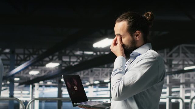 Data center developer frustrated by critical error affecting laptop. Irate server farm worker reacting to hardware performance issues triggered by unresolved software bugs, camera B