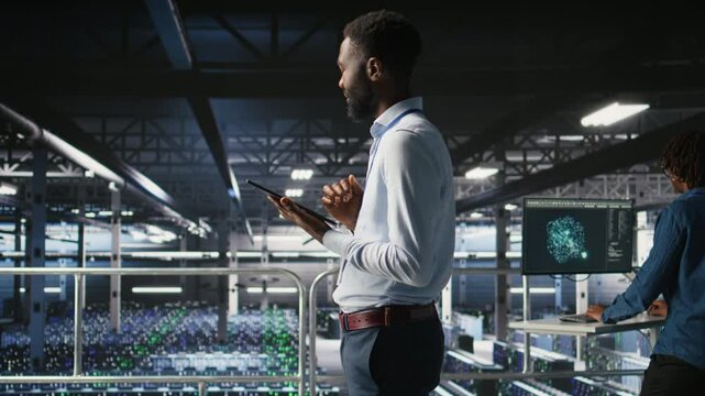 Admin on data center industrial platform analyzing infrastructure performance outputs on tablet. Server room employee doing job tasks, finetuning mainframes configurations, camera A