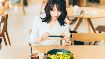 カフェで料理の写真を撮影する女性