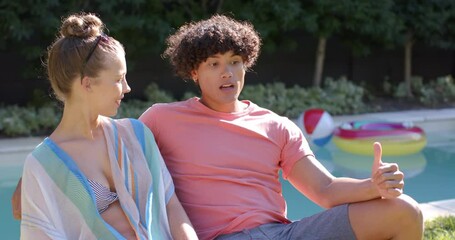 Young diverse couple relaxing by pool, enjoying conversation and sunny day outdoors - Powered by Adobe