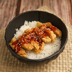 Rice bowl with chicken katsu and topped with sauce and sesame seeds