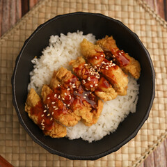 Rice bowl with chicken katsu and topped with sauce and sesame seeds
