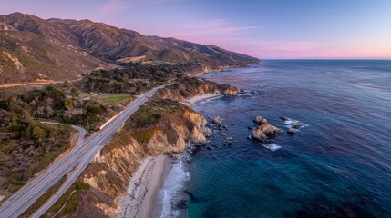 Fototapeta premium Aerial drone view of Big Sur coastal road in California at sunset with winding highway, ocean waves, rolling hills, sandy beaches, mountains and greenery under clear sky and soft warm light