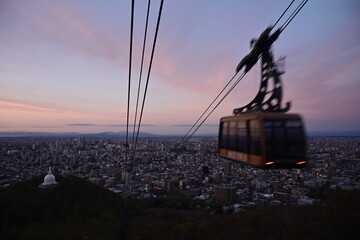 夕暮れに染まる街とロープウェイ