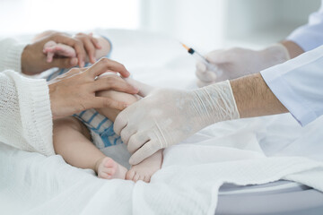 Asian loving mother comforts her three-month-old, as a male doctor administers essential childhood vaccinations, ensuring the baby's healthy future in a calm, professional setting.