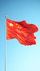 A vibrant red Chinese flag billows majestically against a clear, pale blue sky on a tall flagpole