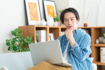 リビングでパソコンを見る若い男性