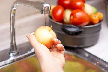 Woman washing organic apple, food disinfection concept