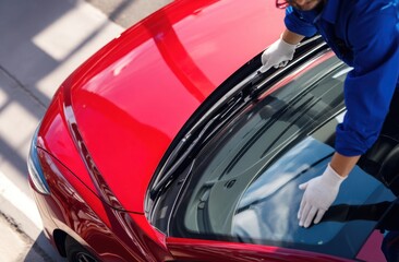 Man cleaning red car windshield with gloves