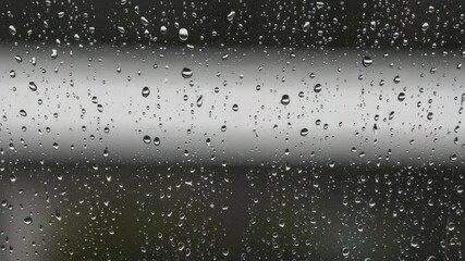 Raindrops sliding down glass surface, creating streaks with natural motion and soft light refraction - Powered by Adobe