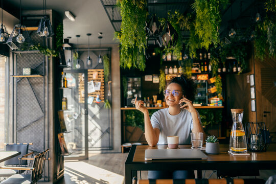 Young stylish interracial girl talking on cellphone in coffee shop.