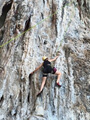 Fototapeta premium climber on the rock Female athlete top rope rock climbing at Railay Beach, Ao Nang, Krabi Province, Thailand.