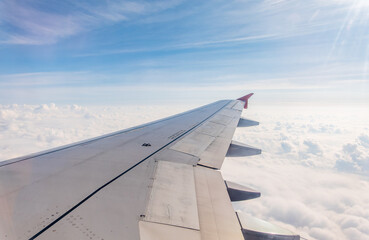 Fototapeta na wymiar View from the airplane window at a beautiful cloudy sky and the airplane wing