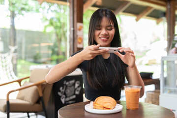 young teenager influencer woman eating breakfast in cafe while taking photo