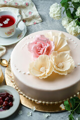 Chocolate biscuit cake with white chocolate,  flower cream and berries on light background. Sweets, dessert and pastry for holiday, top view, close up