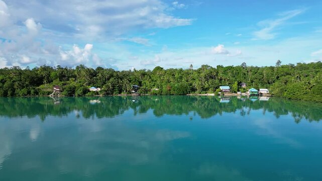 Maratua, Indonesia: Aerial drone footage of the jungle and small village reflection in the turquoise of the Maratua lagoon in the Derawan archipelago in Kalimantan in Indonesia Borneo.
