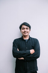 Confident smiling asian man portrait with arms crossed on neutral background