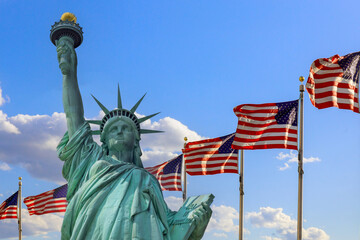 Statue of Liberty rises majestically with American flags fluttering in breeze on Ney York US