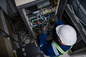 Server expert repair technicians are checking the integrity of server cabinet cable connections to...