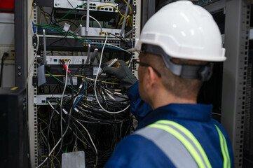 An expert repair technician in the office is connecting the server cabinet cables to ensure the system works properly according to standards.