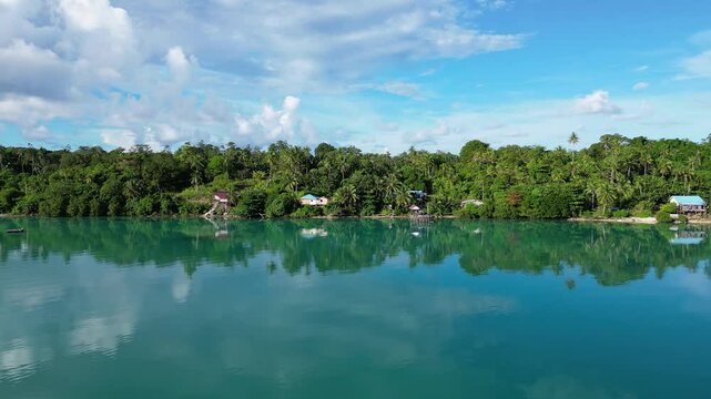 Maratua, Indonesia: Aerial drone footage of the jungle and small village reflection in the turquoise of the Maratua lagoon in the Derawan archipelago in Kalimantan in Indonesia Borneo.