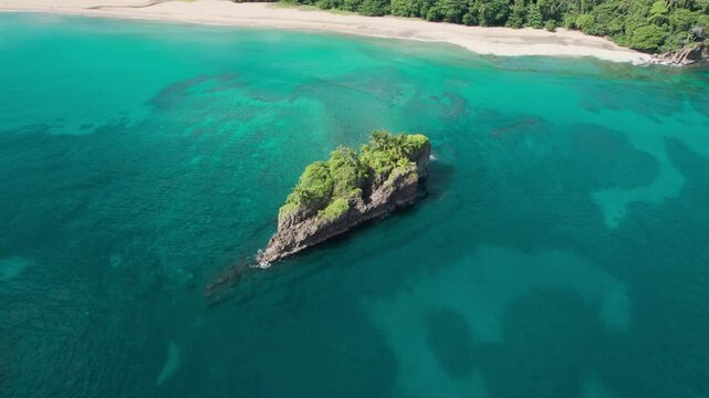 Aerial orbit showcasing Isla Cocles surrounded by vibrant turquoise waters and pristine coastline in Costa Rica.
