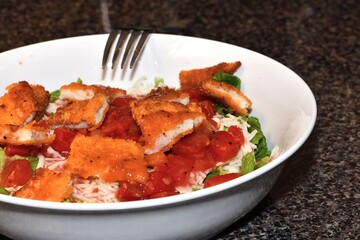 Crispy breaded chicken patties, broken into bite-sized pieces, resting atop a bed of green lettuce.