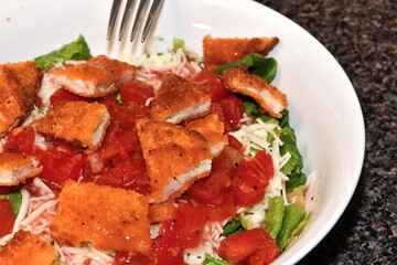 Crispy breaded chicken patties, broken into bite-sized pieces, resting atop a bed of green lettuce.