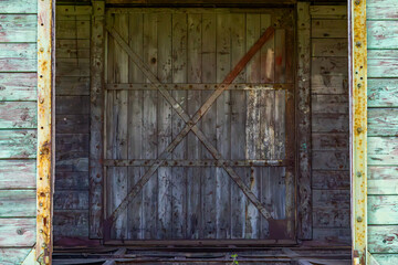 weathered wooden sliding door on an old freight train wagon. The surface shows rusted metal...