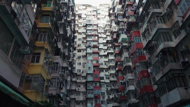 breathtaking vertical view of an iconic housing complex in Hong Kong. Showcasing densely packed residential buildings with balconies, air conditioning units, and colorful facades