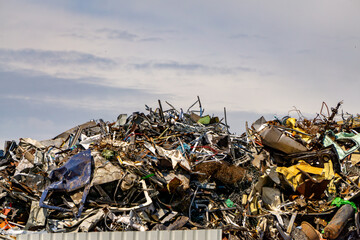 large pile of scrap metal composed of crushed cars, industrial waste, and metal debris. The scene...