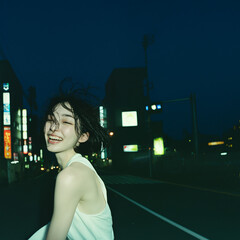 夜の都会を笑顔で歩く若い女性