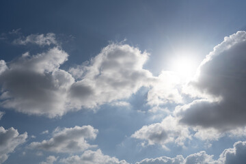 The sun shines brightly through thick white clouds against a deep blue sky. A dramatic and radiant moment capturing the power and contrast of nature's light.